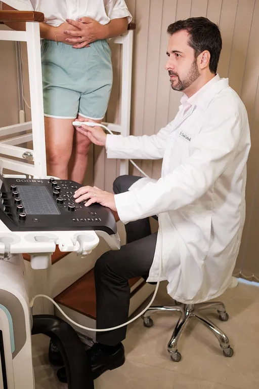 Dr. Danilo Cardinelli realizando ultrassom doppler vascular na perna de uma paciente